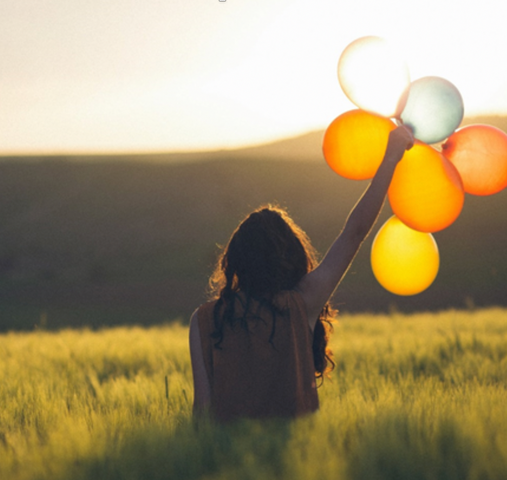 Woman holding balloons. Stop Doing These Things to Transform Your Life