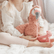 Girl sitting cross legged on a bed with the weighted flamingo propped upright against her