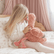 Girl kneeling on a bed, face to face with the weighted flamingo she is holding