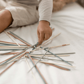 Child carefully picking a single stick from the pile on a bed
