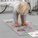 Child bending forward to touch their toes on the grey Nature mat, with a yoga card beside them