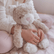 Child sitting on a bed with the cream weighted cat propped beside them