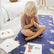 Child kneeling on the navy Space mat with palms together, yoga cards spread on the floor