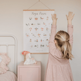 Girl reaching up beside the Yoga Poses print hanging on her bedroom wall