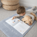 Child lying on the grey Coal mat with a plush dog, turning the pages of an open book