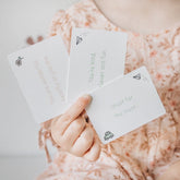 Child holding a fan of Love Notes cards including Shoot for the moon and You're kind, clever and fun
