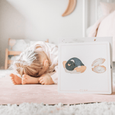 Child in child's pose on a pink rug beside the Clam yoga card