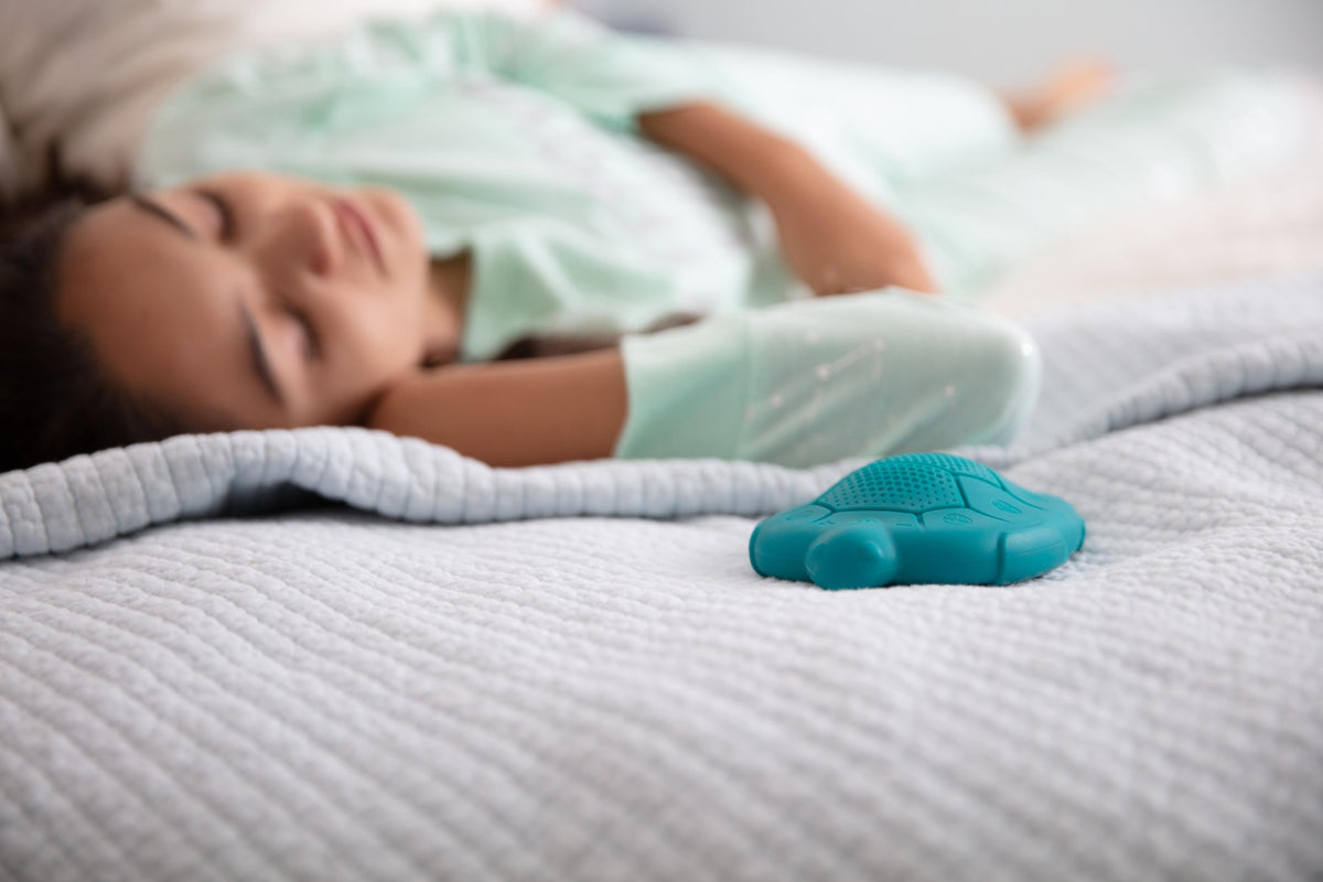 A child asleep on a bed beside a teal Zenimal Kids+