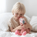 Child sitting up in bed, smiling and resting their cheek against the pink weighted flamingo