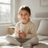 Girl sitting cross legged on a bed holding the essential oil roller