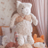 Child holding the weighted cat up by its front paws, with other weighted plush animals on the bed behind