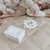 Two children playing the yoga snap card game on a quilted mat