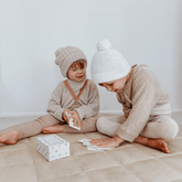 Two children laying out yoga snap cards on the floor beside the box