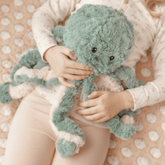 Child sitting cross legged holding the teal weighted octopus against their front