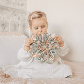 Toddler sitting on a bed holding the magic ball in its closed position