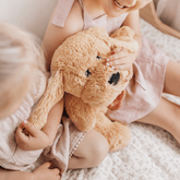 Child sitting on a bed hugging the weighted puppy against their chest