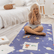 Child sitting cross legged on the navy Space mat with hands pressed together, yoga cards laid out nearby