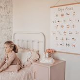The Yoga Poses print hanging above a pink nightstand in a child's bedroom