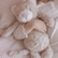 Child's arm wrapped around the cream weighted cat lying on a striped bed sheet