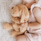 Toddler lying on a bed hugging the golden weighted puppy