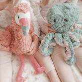 Close up of a child holding the pink weighted flamingo beside the teal weighted octopus