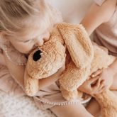 Child resting their face against the weighted puppy's head