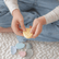 Child pressing a thumb into a yellow textured worry stone, with more stones on the blanket below
