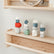 Patience Pebbles stacked into three small towers on a wooden shelf in red, grey, green, white and blue