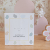 Worry Stones box standing on a wooden shelf beside a pink flower decoration