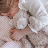 Girl lying on a striped pillow with her arm around the weighted cat