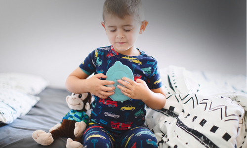 Child holding a Zenimal on a bed with a neutral background