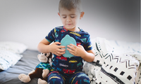 Child holding a Zenimal on a bed with a neutral background