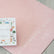 The pink yoga mat unrolled on a floor with a box of yoga cards resting on it
