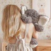 Girl seen from behind carrying the weighted elephant over her shoulder