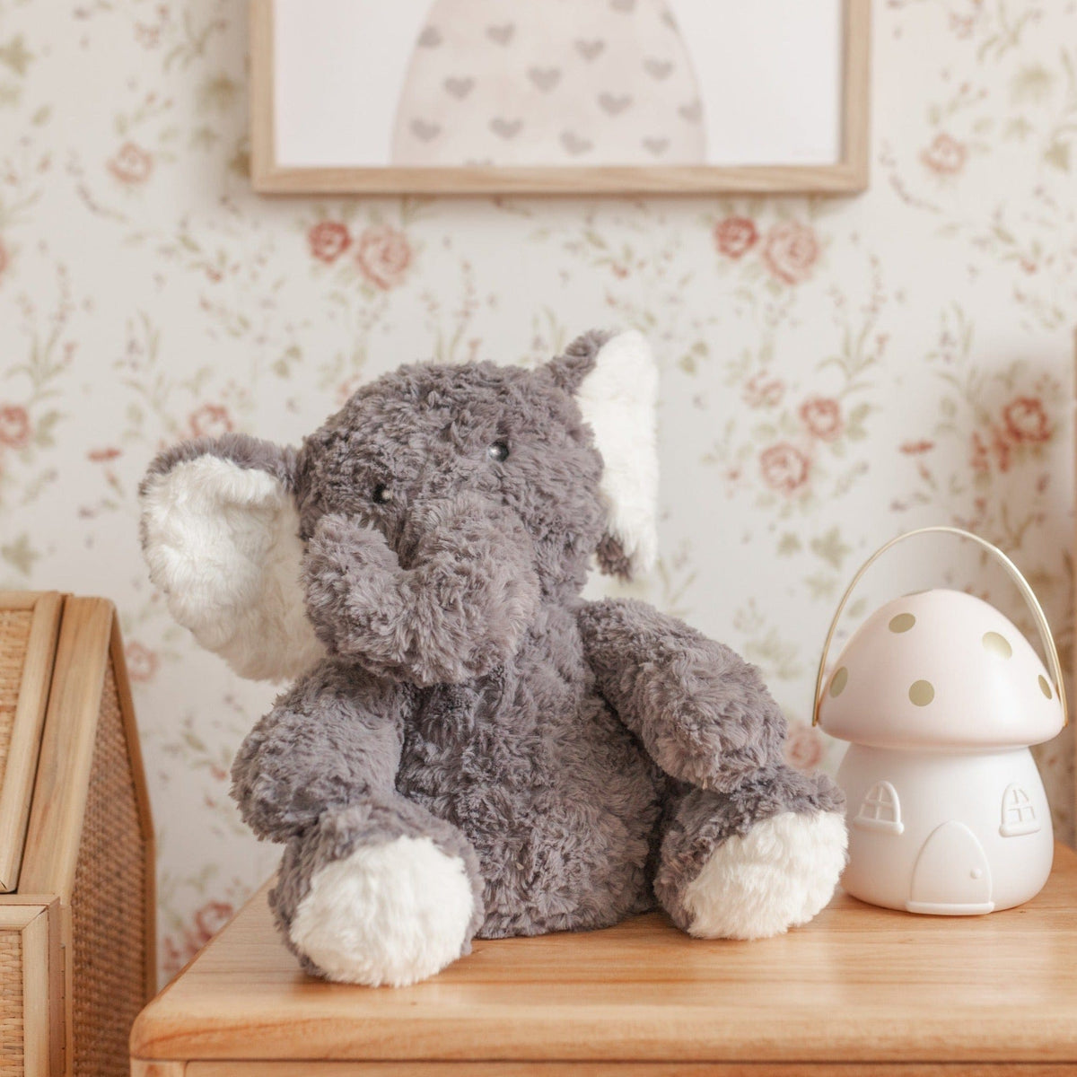 The grey weighted elephant sitting on a wooden table beside a mushroom shaped nightlight