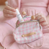 Child tucking the essential oil roller into a pink gingham purse