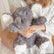 Child sitting on a bed holding the grey weighted elephant in their lap
