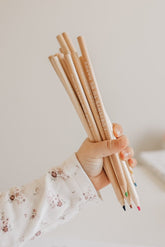 Child's hand holding a bunch of the wooden affirmation pencils