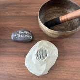 Cream Zenimal+ on a wooden table beside a singing bowl and a painted stone reading Breathe, it'll be okay.