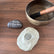 Cream Zenimal+ on a wooden table beside a singing bowl and a painted stone reading Breathe, it'll be okay.
