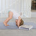 Child in downward dog on the blue grey mat beside an open box of yoga cards