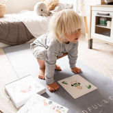 Toddler in downward dog on a grey mat with yoga cards laid out on the floor
