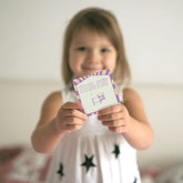 Young girl smiling and holding up an I'm a good dreamer affirmation card