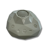 Sage gray faceted Zenimal+ device for teens and adults, angled view showing the round speaker grille, power and volume buttons, and embossed track icons