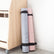 Two rolled yoga mats, grey and pink, stored upright beside a wooden cabinet