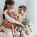 Two children sitting on a bed hugging the flamingo, puppy and octopus plush toys.