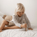 Child kneeling on a bed holding the bundle of sticks upright before dropping them