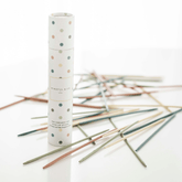 The Pick Up Sticks tube standing beside a scatter of the wooden sticks