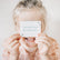 Child holding a Love Note over their eyes reading you're full of bright ideas and big dreams