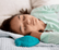 Girl with dark hair asleep in mint pajamas with a teal turtle shaped Zenimal resting beside her on the bed